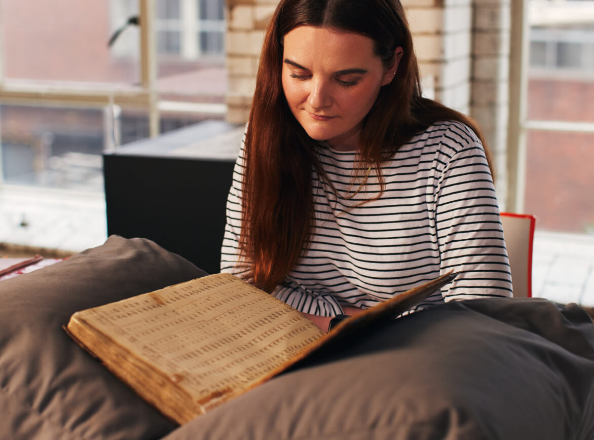 Woman consulting brewing ledger in the Guinness Archive research room. 