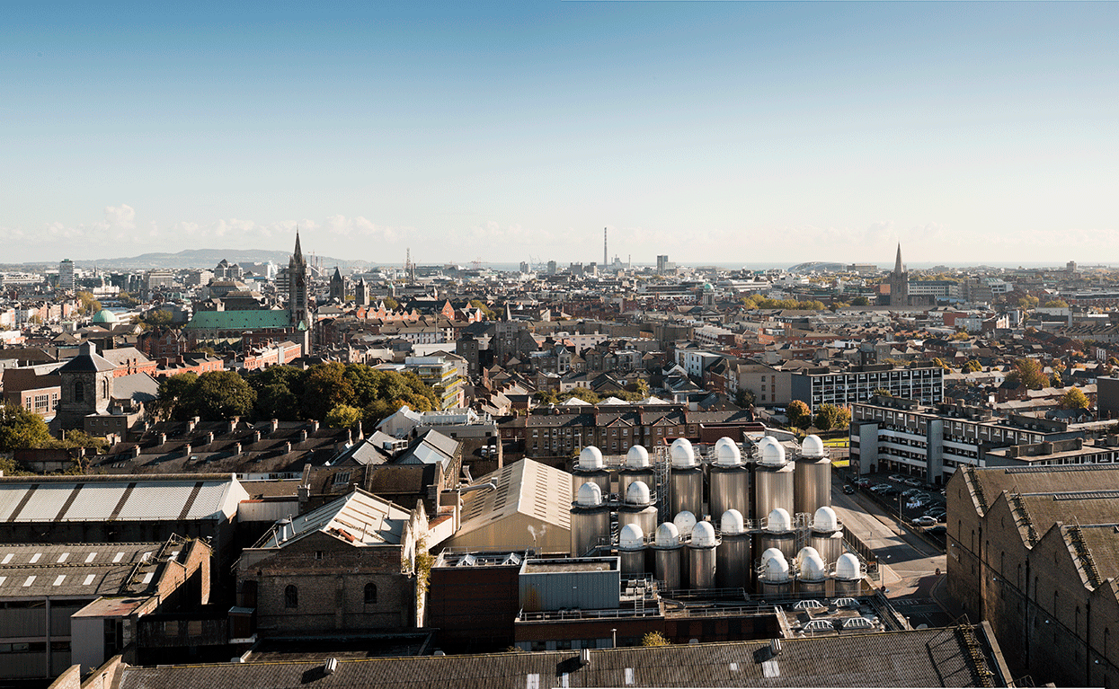 An aerial view of the Liberties, with the Roe & Co Distillery and the windmill visible, in front of a cloudy blue sky